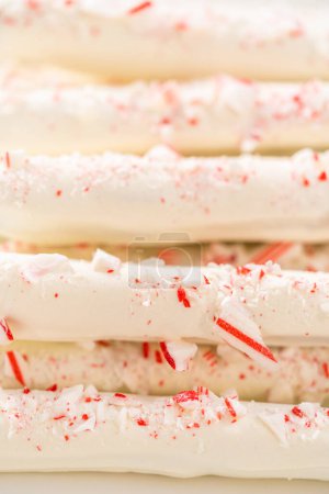 Photo for Pile of homemade candy cane chocolate-covered pretzel rods on a white serving plate. - Royalty Free Image