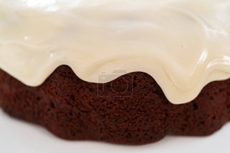 Foto de Verter esmalte de queso crema sobre pastel de terciopelo rojo recién horneado. - Imagen libre de derechos