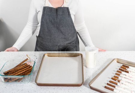 Téléchargez les photos : Tremper les tiges de bretzel dans du chocolat fondu et saupoudrer de bonbons de canne à sucre écrasés pour faire des tiges de bretzel recouvertes de chocolat de canne à sucre. - en image libre de droit