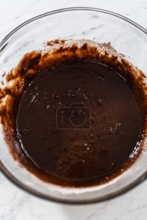 Téléchargez les photos : Mélanger les ingrédients secs et humides avec un fouet à la main dans un bol de mélange en verre pour cuire des brownies à la menthe poivrée. - en image libre de droit
