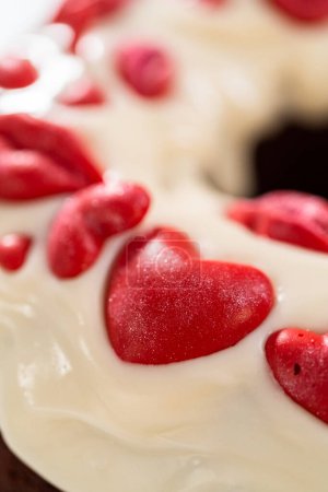 Foto de Freshly baked red velvet bundt cake with chocolate lips and hearts over cream cheese glaze for Valentines Day. - Imagen libre de derechos
