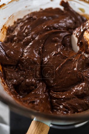 Téléchargez les photos : Faire fondre les pépites de chocolat blanc et d'autres ingrédients dans un bol de mélange en verre sur de l'eau bouillante pour préparer le fudge macadamia au chocolat. - en image libre de droit