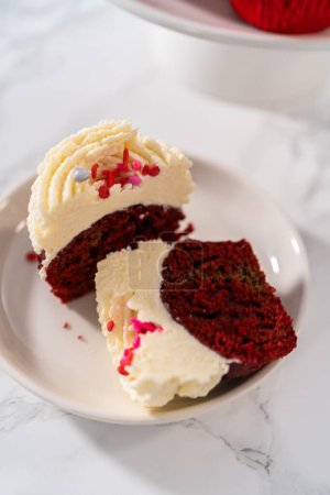 Photo for Sliced red velvet cupcakes with white chocolate ganache frosting on a white plate. - Royalty Free Image