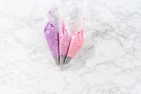 Photo for Flat lay. Ombre pink buttercream frosting in a piping bag with a jumbo metal piping tip. - Royalty Free Image