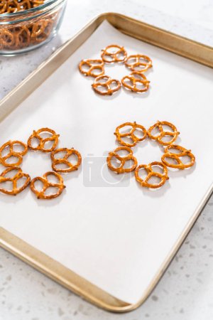Foto de Dipping pretzels twists into melted chocolate to make a chocolate pretzel Christmas wreath. - Imagen libre de derechos