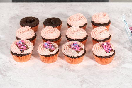 Téléchargez les photos : Glaçage à la crème au beurre à la fraise sur des cupcakes au chocolat. - en image libre de droit
