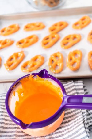 Photo for Dipping pretzels twists into melted chocolate to make chocolate-covered pretzel twists. - Royalty Free Image