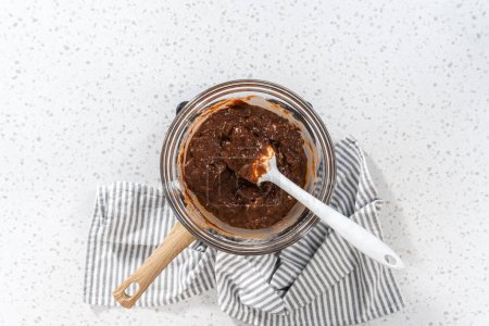 Photo for Flat lay. Melting chocolate chips and other ingredients in a glass mixing bowl over boiling water to prepare plain fudge. - Royalty Free Image