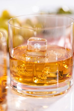 Foto de Escocés en las rocas en vaso de whisky sobre una superficie de mármol blanco. - Imagen libre de derechos