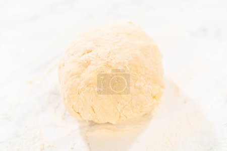 Téléchargez les photos : Rouler la pâte à pain avec un rouleau à pâtisserie français pour cuire des petits gâteaux à la cannelle sans levure. - en image libre de droit