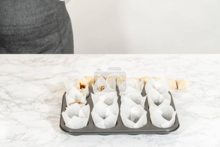 Foto de Relleno de forros de cupcakes con pequeños rollos de canela para hornear cupcakes de canela sin levadura. - Imagen libre de derechos