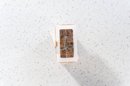 Photo for Flat lay. Packaging homemade chocolate fudge with peanut butter swirl into a white gift box. - Royalty Free Image