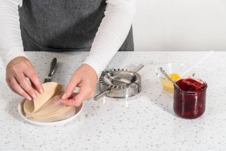 Photo for Filling empanada dough with cherry pie filling to make sweet cherry empanadas in the air fryer. - Royalty Free Image