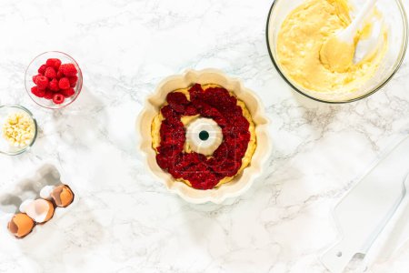 Photo for Flat lay. After greasing the bundt cake pan, its time to fill it with the prepared cake batter and delightful raspberry cake filling - creating a perfect harmony of flavors. - Royalty Free Image
