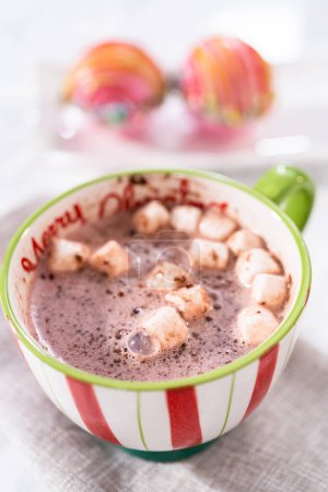 Téléchargez les photos : Préparation de bombes au chocolat chaud de Noël avec du lait chaud dans une tasse de Noël. - en image libre de droit