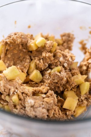 Photo for Mixing ingredients in a large glass mixing bowl to bake apple oatmeal cookies. - Royalty Free Image