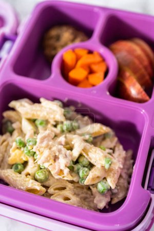 Foto de Comida escolar bento box con macarrones ensalada con pollo y manzanas. - Imagen libre de derechos