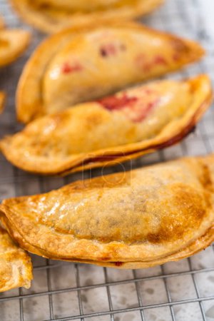 Téléchargez les photos : Empanadas de cerises douces fraîchement cuites dans la friteuse sur le comptoir de la cuisine. - en image libre de droit