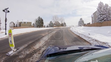 Foto de Al atravesar una carretera suburbana recién despejada después de una tormenta de invierno, uno experimenta un viaje sereno a través de un exclusivo vecindario residencial. Casas cubiertas de nieve y árboles contribuyen a un pintoresco - Imagen libre de derechos