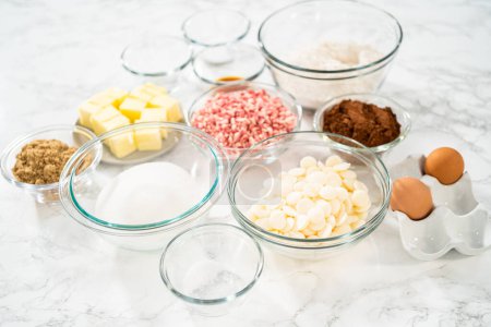 Gemessene Zutaten in einer gläsernen Rührschüssel zur Zubereitung von pfefferminzweißen Schokoladenkeksen.