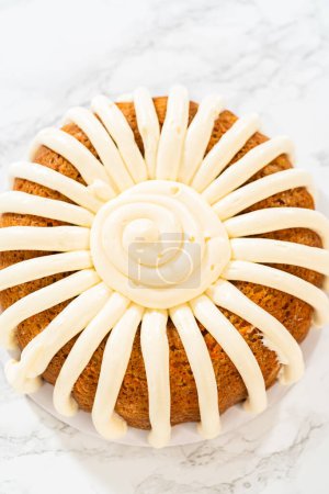 Téléchargez les photos : Le gâteau Bundt aux carottes fraîchement cuit est magnifiquement givré avec une couche luxuriante de glaçage au fromage à la crème. - en image libre de droit