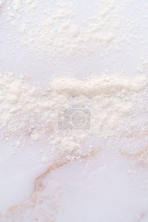 Photo for White flour sprinkled over the pink marble surface during the baking. - Royalty Free Image