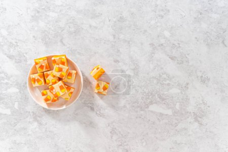Foto de Flat lay. Homemade candy corn fudge square pieces on a white plate. - Imagen libre de derechos