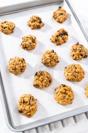 Photo for Cooling freshly baked soft oatmeal raisin walnut cookies on a kitchen counter. - Royalty Free Image