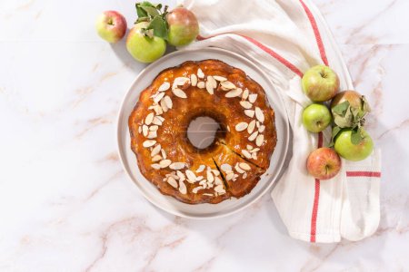 Photo for Flat lay. Freshly baked apple bundt cake with caramel glaze on a white plate. - Royalty Free Image