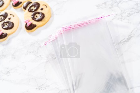 Téléchargez les photos : Emballage de biscuits sablés en forme de panda avec glaçage au chocolat dans des sacs transparents individuels. - en image libre de droit