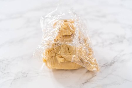 Foto de Envolver la masa de galletas en una envoltura de celofán para transferirla al refrigerador para enfriarla.. - Imagen libre de derechos