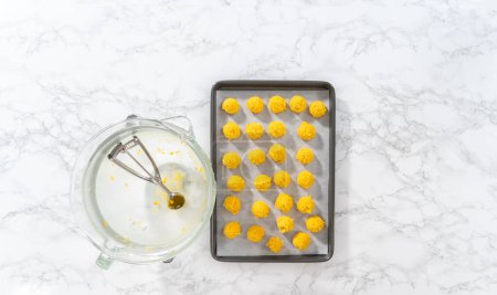 Photo for Lemon Cookies with White Chocolate. Flat lay. Scooping cookie dough with dough scoop into a baking sheet lined with parchment paper to bake lemon cookies with white chocolate. - Royalty Free Image