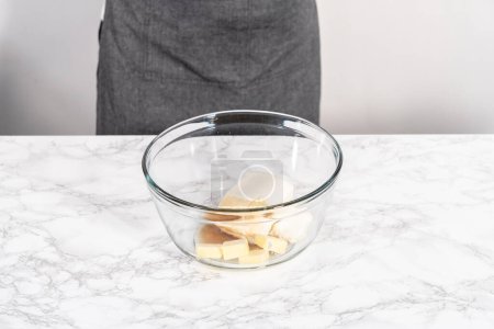 Téléchargez les photos : Mélanger les ingrédients dans un grand bol à mélanger en verre pour préparer le glaçage au fromage à la crème. - en image libre de droit