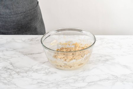 Foto de Mezclar ingredientes húmedos y secos con un batidor de mano en un tazón de vidrio para hornear magdalenas de semillas de amapola de limón. - Imagen libre de derechos