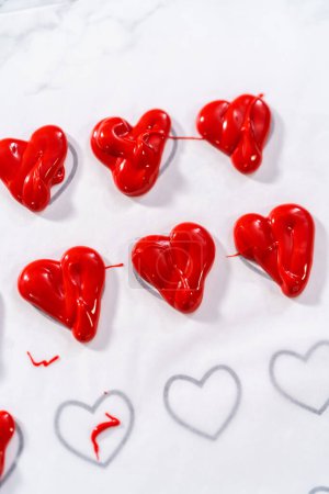 Foto de Tubería de chocolate derretido de tuberías de nuevo sobre el papel de pergamino para hacer un corazón de chocolate. - Imagen libre de derechos