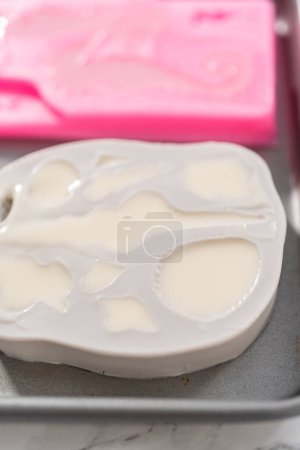 Foto de Relleno de moldes de chocolate de silicona en forma de colas de sirena y conchas marinas con chocolate derretido. - Imagen libre de derechos