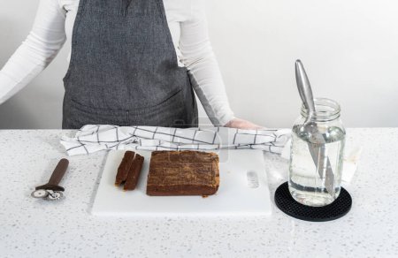 Foto de Cortar la mantequilla de cacahuete de chocolate en trozos pequeños en una tabla de cortar blanca. - Imagen libre de derechos