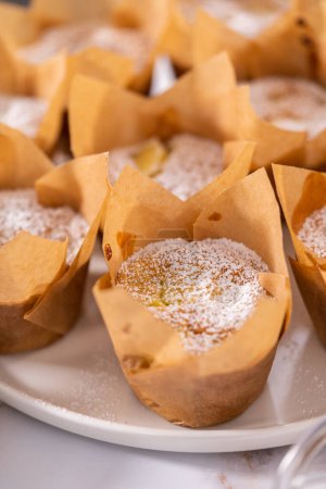 Foto de Decorar magdalenas sharlotka de manzana recién horneadas espolvoreadas con azúcar en polvo. - Imagen libre de derechos