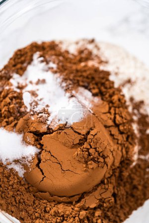 Photo for Mixing dry ingredients in a large glass mixing bowl to bake chocolate cookies with chocolate hearts for Valentines Day. - Royalty Free Image
