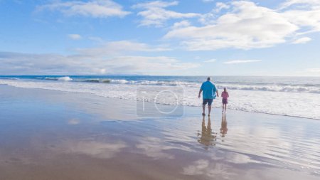 Photo for In California, a father and daughter share a serene winter walk along the deserted sands of El Capitan State Beach. - Royalty Free Image
