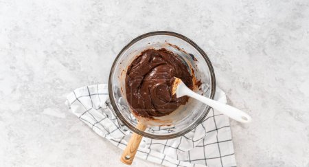 Photo for Flat lay. Melting white chocolate chips and other ingredients in a glass mixing bowl over boiling water to prepare chocolate macadamia fudge. - Royalty Free Image