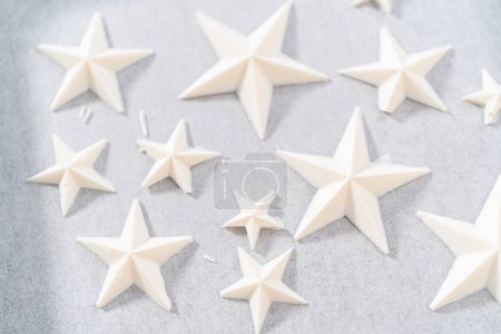 Foto de Filling silicone mold with white melted chocolate to make chocolate chocolate stars for American flag mini cupcakes. - Imagen libre de derechos