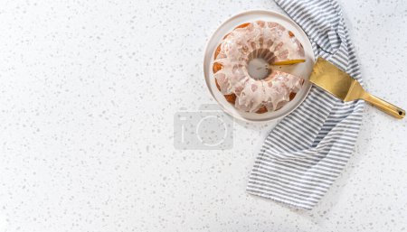 Photo for Flat lay. Sliced vanilla bundt cake with a vanilla glaze on a white plate. - Royalty Free Image