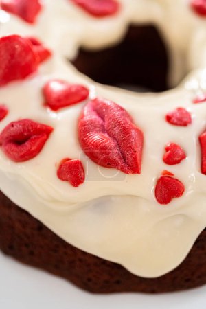 Foto de Freshly baked red velvet bundt cake with chocolate lips and hearts over cream cheese glaze for Valentines Day. - Imagen libre de derechos