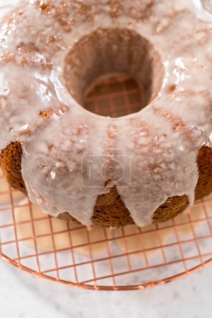 Photo for Glazing vanilla bundt cake with a white vanilla glaze. - Royalty Free Image