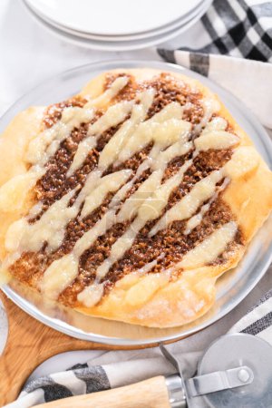 Téléchargez les photos : Pizza dessert à la cannelle fraîchement cuite avec un filet de fromage à la crème. - en image libre de droit