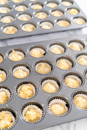 Foto de Scooping cupcake batter with dough scoop into a baking pan with liners to bake American flag mini cupcakes. - Imagen libre de derechos