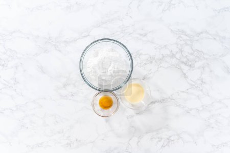 Foto de Acostado. Ingredientes medidos en cuencos de vidrio para hacer glaseado de ponche de huevo. - Imagen libre de derechos