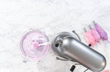 Foto de Acostado. Mezcla de ingredientes en la cocina mezclador eléctrico para hacer ombre rosa crema de mantequilla glaseado. - Imagen libre de derechos