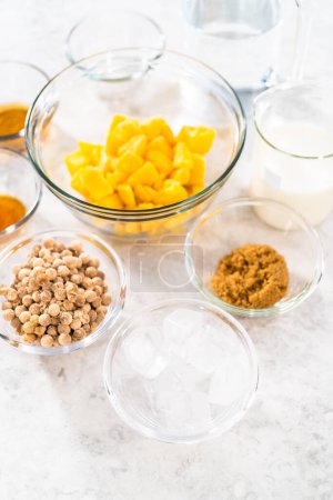Foto de Flat lay. Measured ingredients in glass mixing bowls to prepare mango boba smoothie. - Imagen libre de derechos
